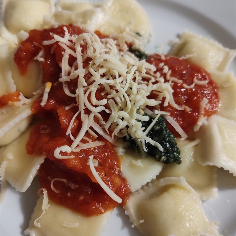 Plato de ravioles frescos con salsa de tomate y queso rallado